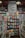 A well-organized bookstore shelf filled with a variety of books. The central section has a display with books displayed with covers facing forward, showcasing titles from different genres and authors. Above the books, there is a large sign featuring the names of famous authors in bold, such as William Shakespeare and Jane Austen. The surrounding shelves are filled with more books arranged side-by-side.