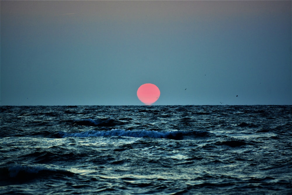 a pink moon over the ocean