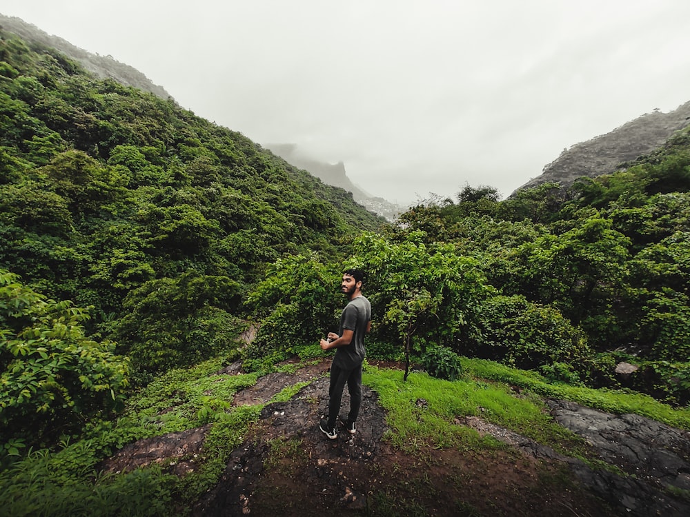 a man standing on a dirt path in a forest