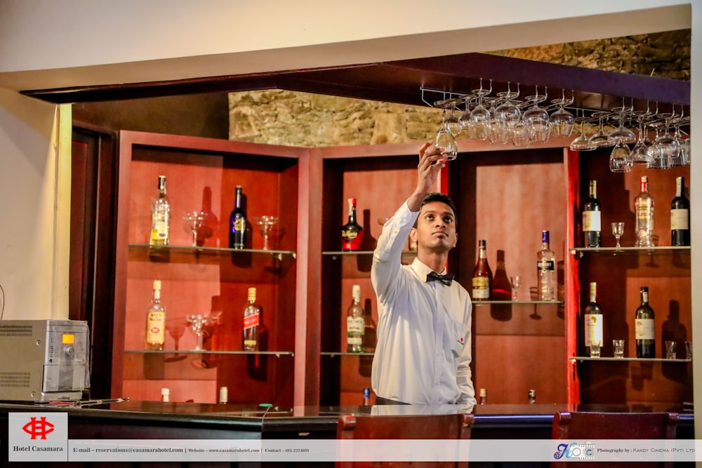 a man standing in front of a bar with many bottles of alcohol