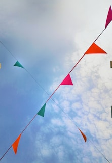 Close-up of a vibrant orange banner trailing a paramotor above a lively outdoor event.