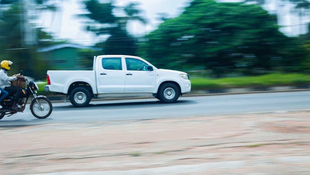 a man riding a motorcycle next to a white truck