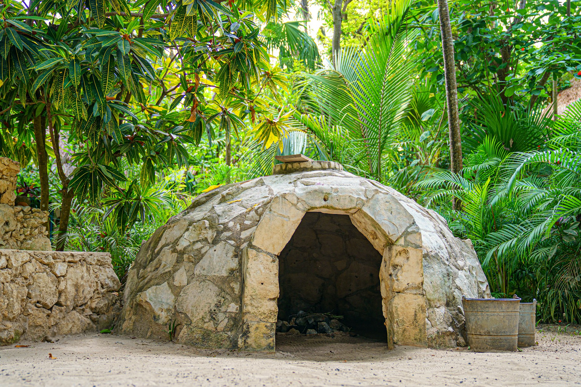 Un temazcal de piedra en forma de domo con una puerta baja en un jardín, como los que se ofrecen en Tepoztlán