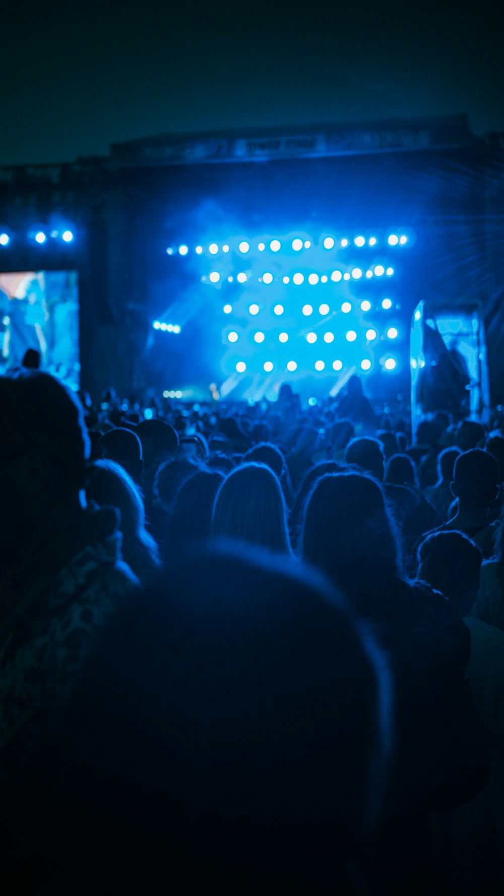 a crowd of people in front of a stage with lights