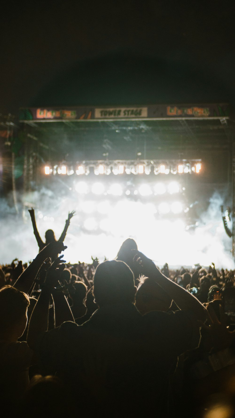 a crowd of people in front of a stage with a large screen