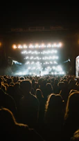 Evening outdoor performance under warm amber stage lights with an engaged audience.