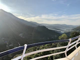 A cozy hotel balcony overlooking lush green hills under a clear blue sky.