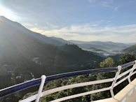 A spacious balcony overlooking misty Mussoorie hills at sunrise, with comfortable seating.
