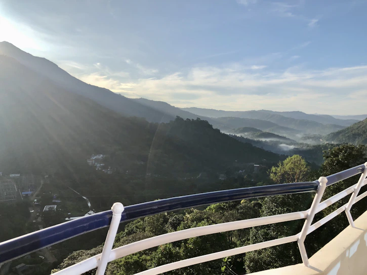 Sunrise view from a hotel balcony overlooking lush Himalayan valleys with soft morning light.