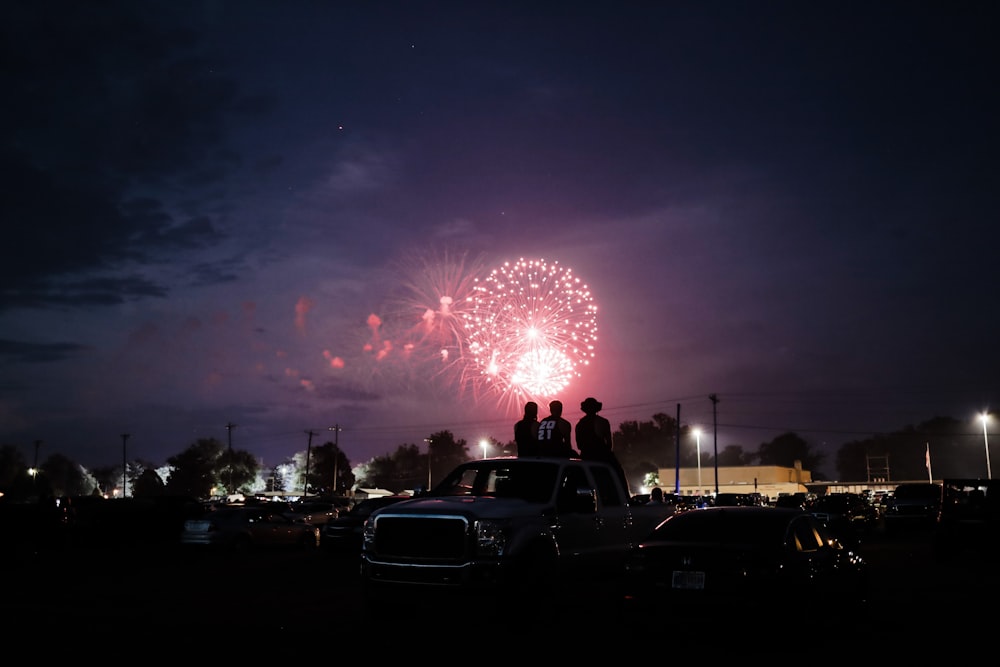 a group of people on a car at night with fireworks in the sky