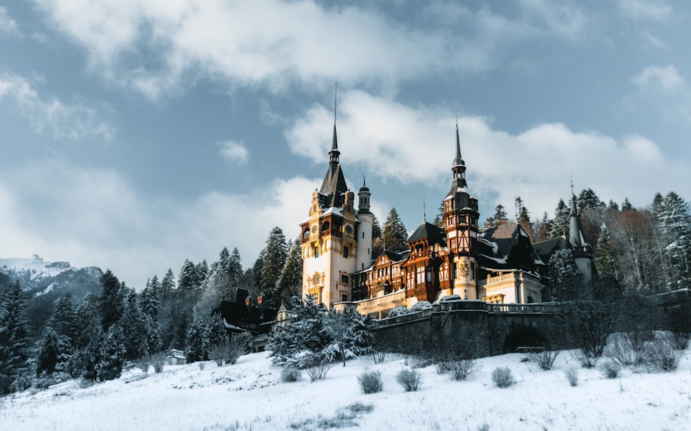 um castelo na neve com o castelo de Peleș ao fundo