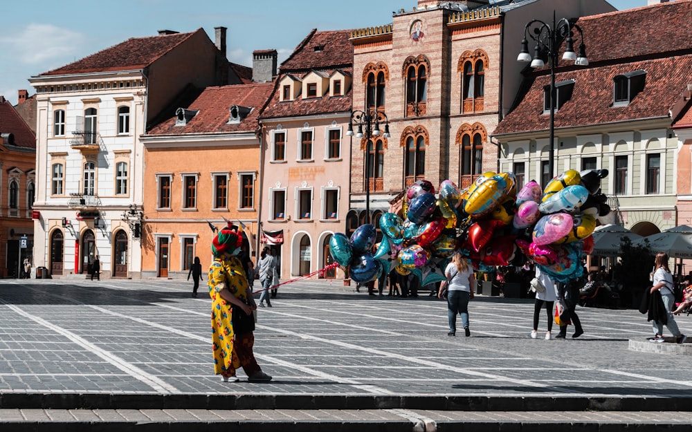 a group of people in clothing walking in a street with buildings