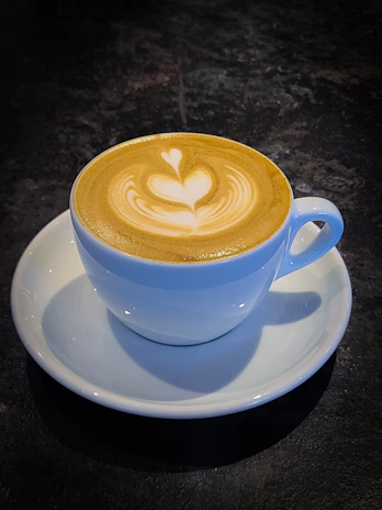 A creamy cappuccino topped with delicate latte art in a sleek black cup.