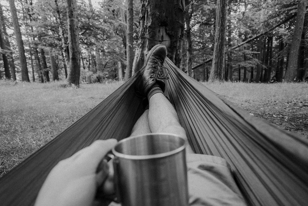 a person's feet on a wooden bench in a forest