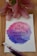 A handwritten quote on a piece of paper with a watercolor background in shades of pink and blue, surrounded by pink lilies and art brushes. The quote reads, 'I will walk by faith even when I cannot see.'