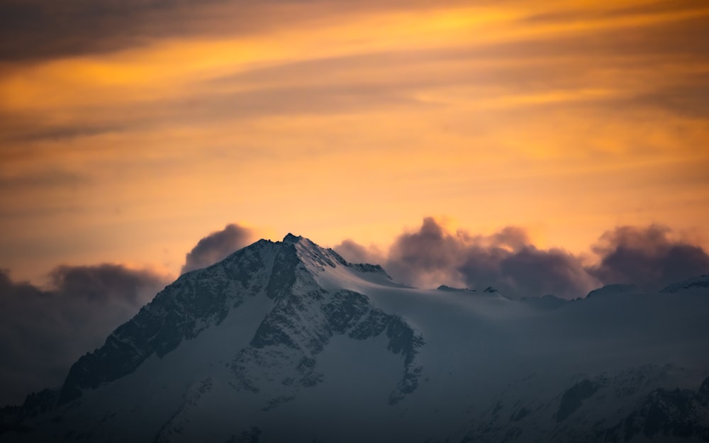 a snowy mountain with clouds