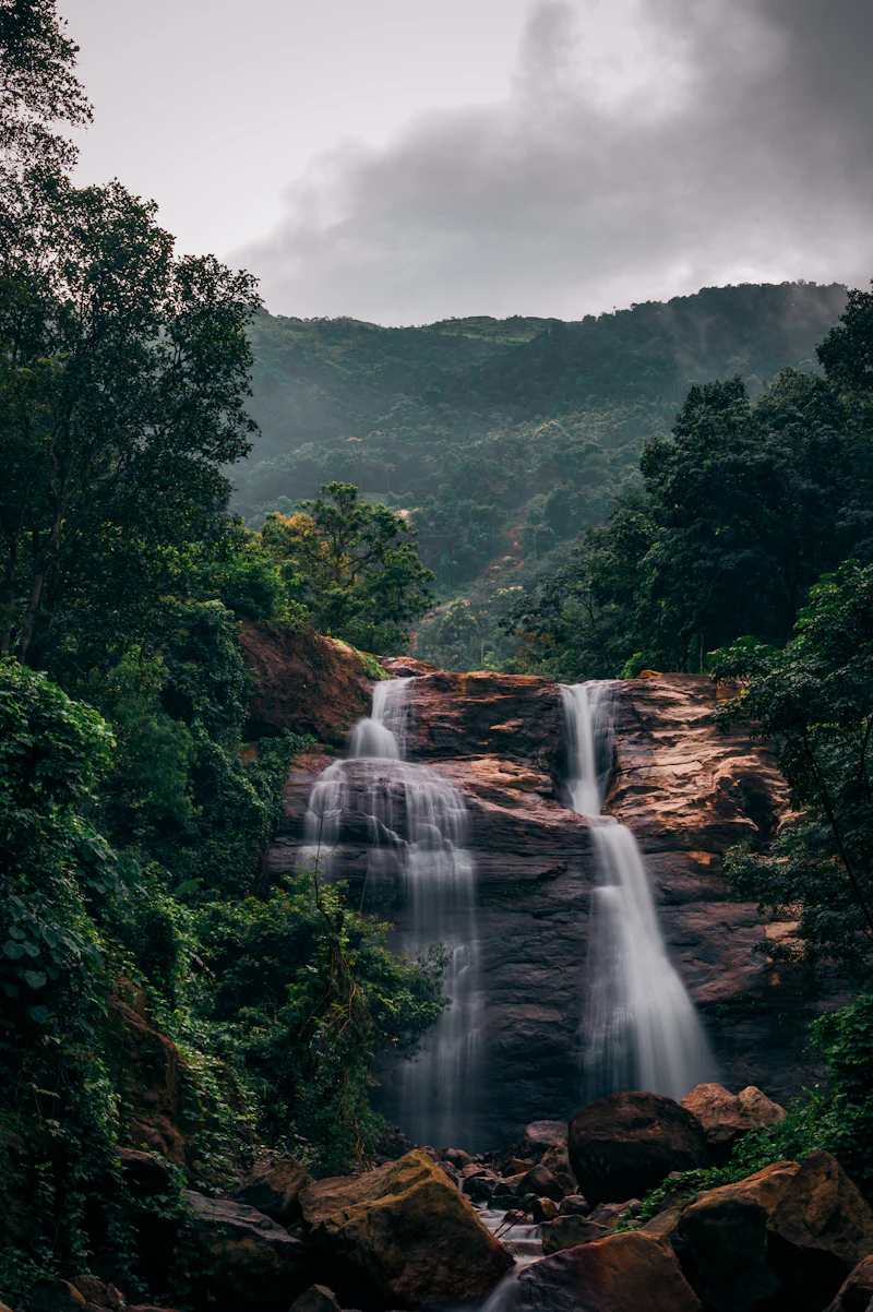 A waterfall spilling over rust-coloured rock deep in the forest