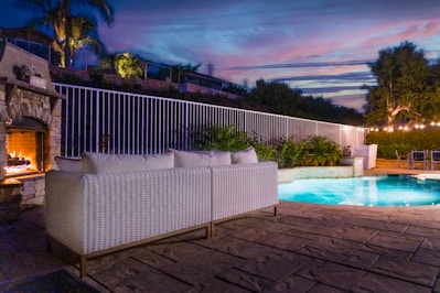 a patio with a pool and a deck with a house in the background
