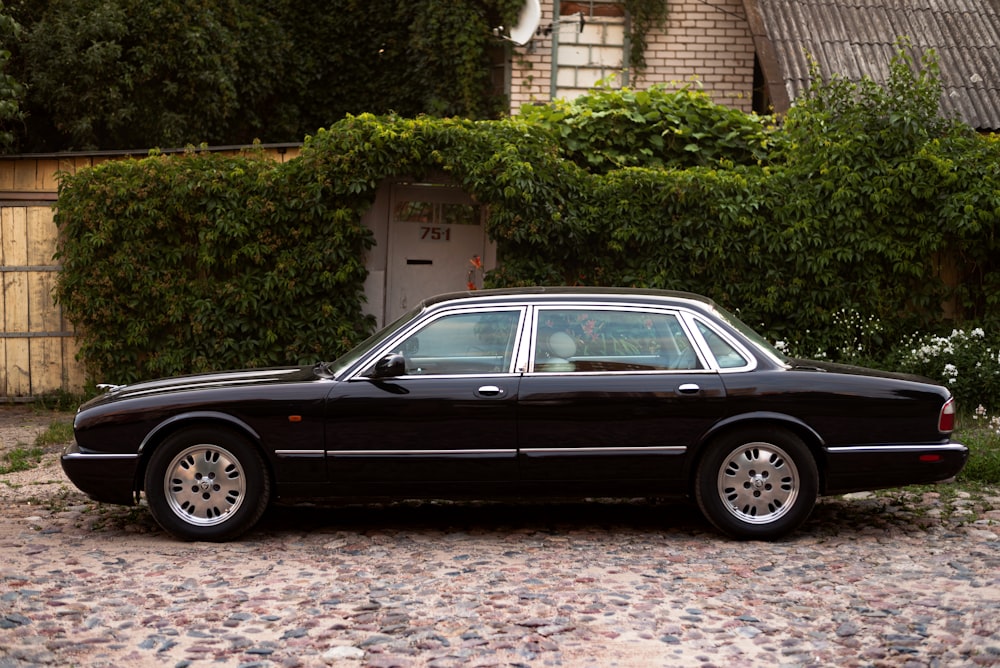 a black car parked in front of a hedge