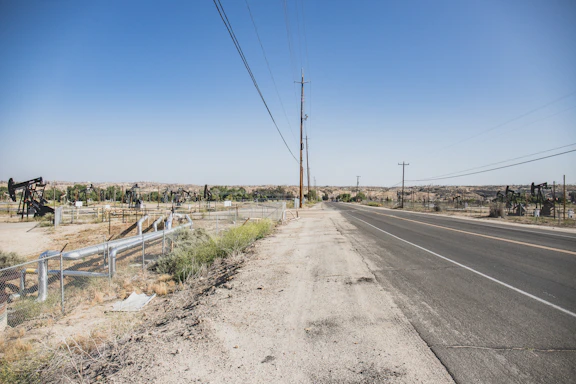 A field agent discussing with landowners near a Texas oil pipeline under the wide, open sky.