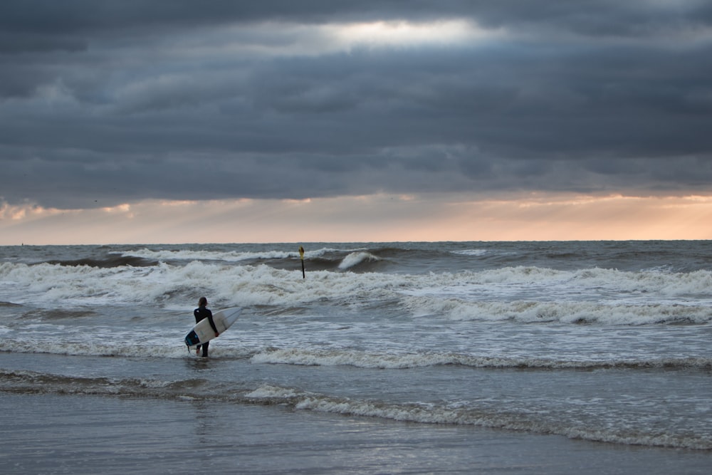 Un hombre cargando una tabla de surf en la playa