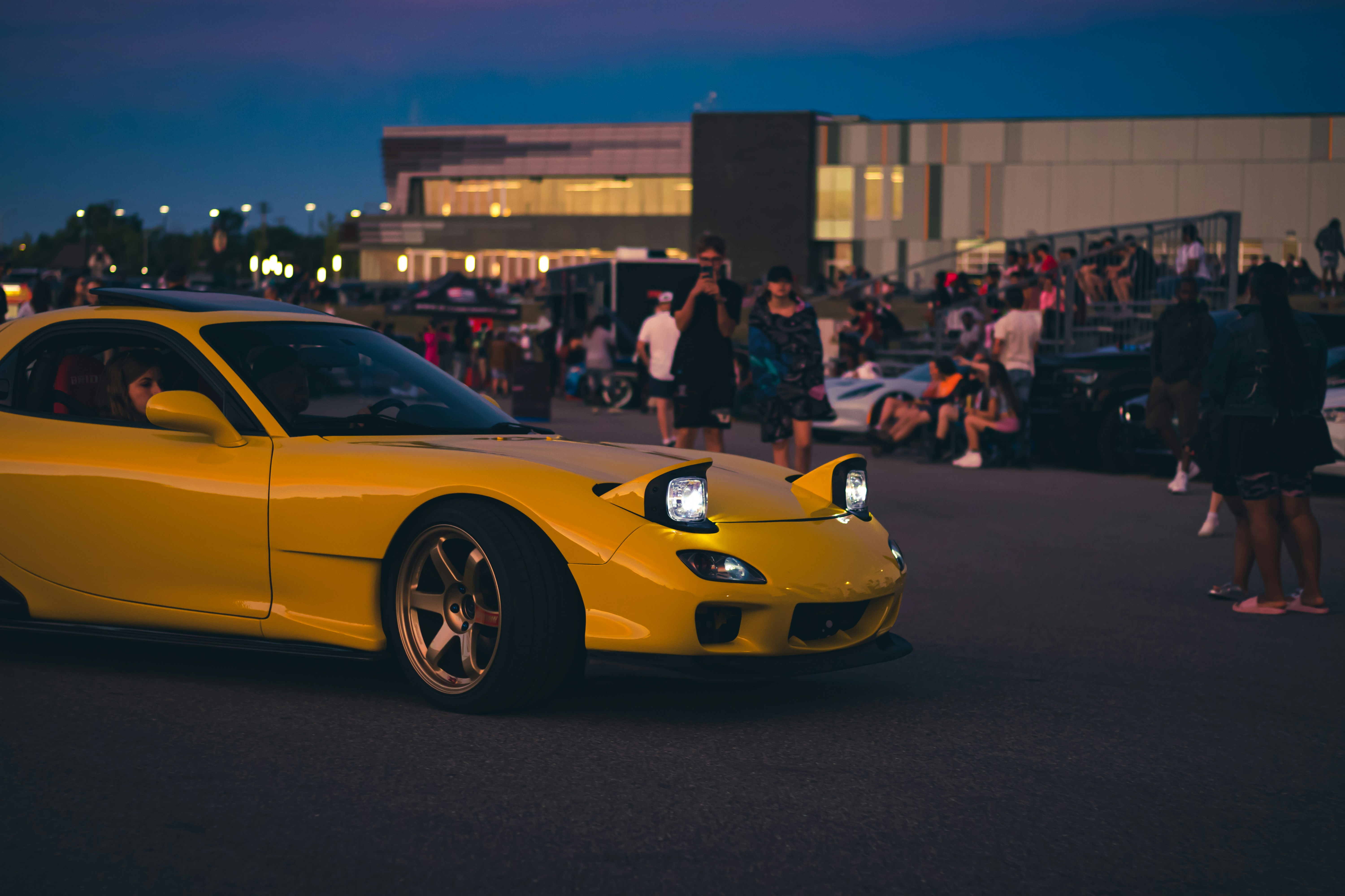 a yellow sports car parked in front of a crowd of people