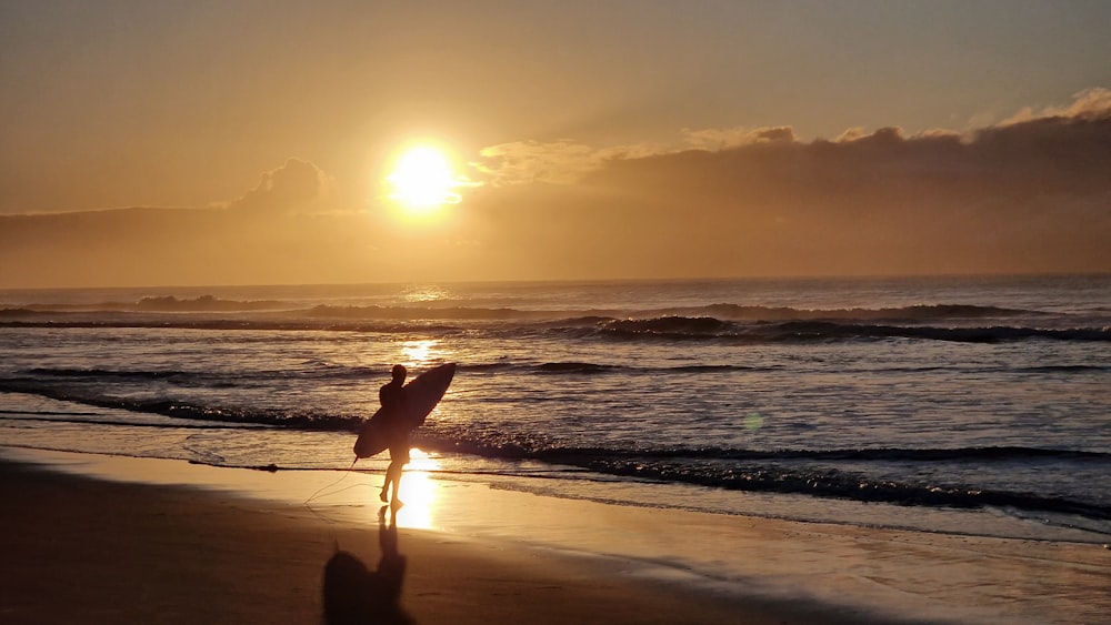 a couple of people carrying surfboards on a beach