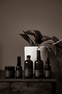 Bottles of dark, rich pyroligneous extract arranged on a wooden table with green plants in the background