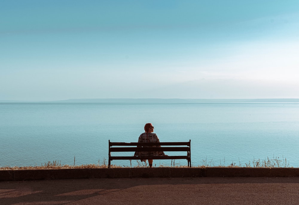 a person sitting on a bench looking at the water
