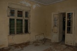 An empty hotel room with a visibly damaged door lock and unsecured window.
