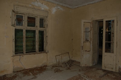 An empty hotel room with a visibly damaged door lock and unsecured window.
