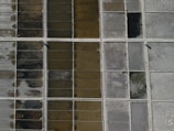 An aerial view of a grid-like pattern consisting of rectangular sections filled with different earthy tones, possibly representing salt pans or agricultural plots. The sections vary in color from dark brown to light gray, with divider lines creating a structured layout.