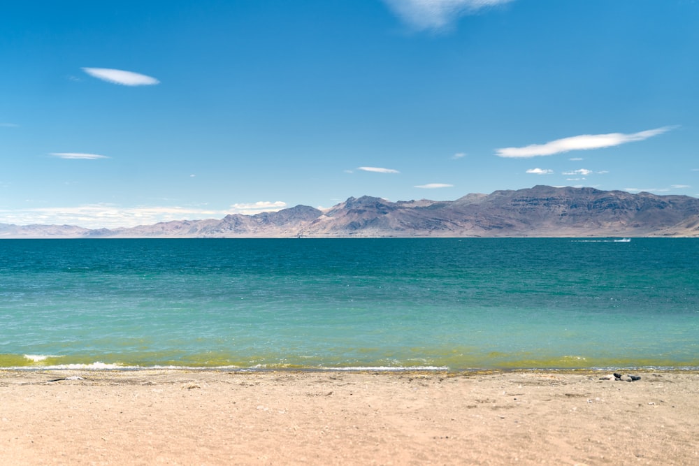 a beach with a body of water and mountains in the background