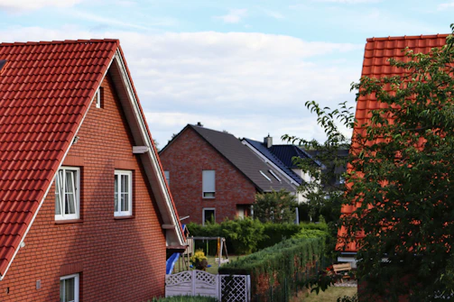 A friendly roofer discussing a project with a homeowner in a sunny suburban neighborhood.
