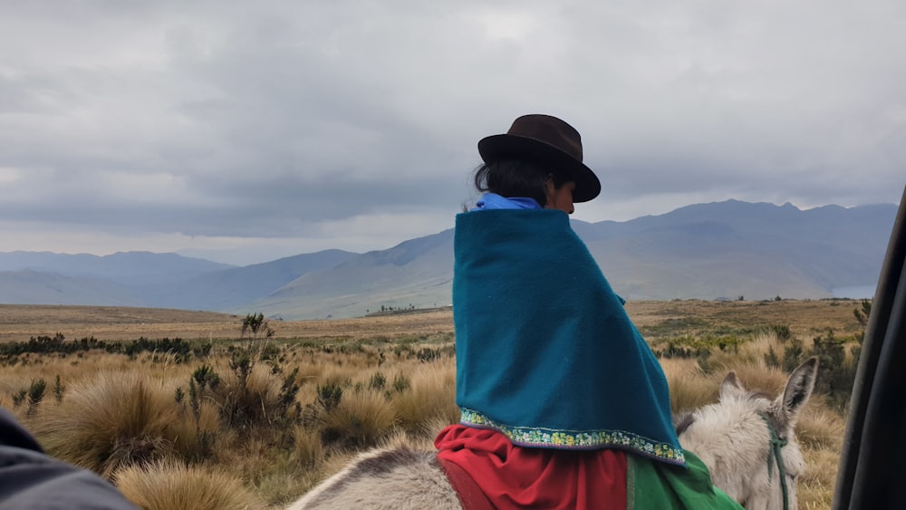 a person in a hat and coat looking at a llama