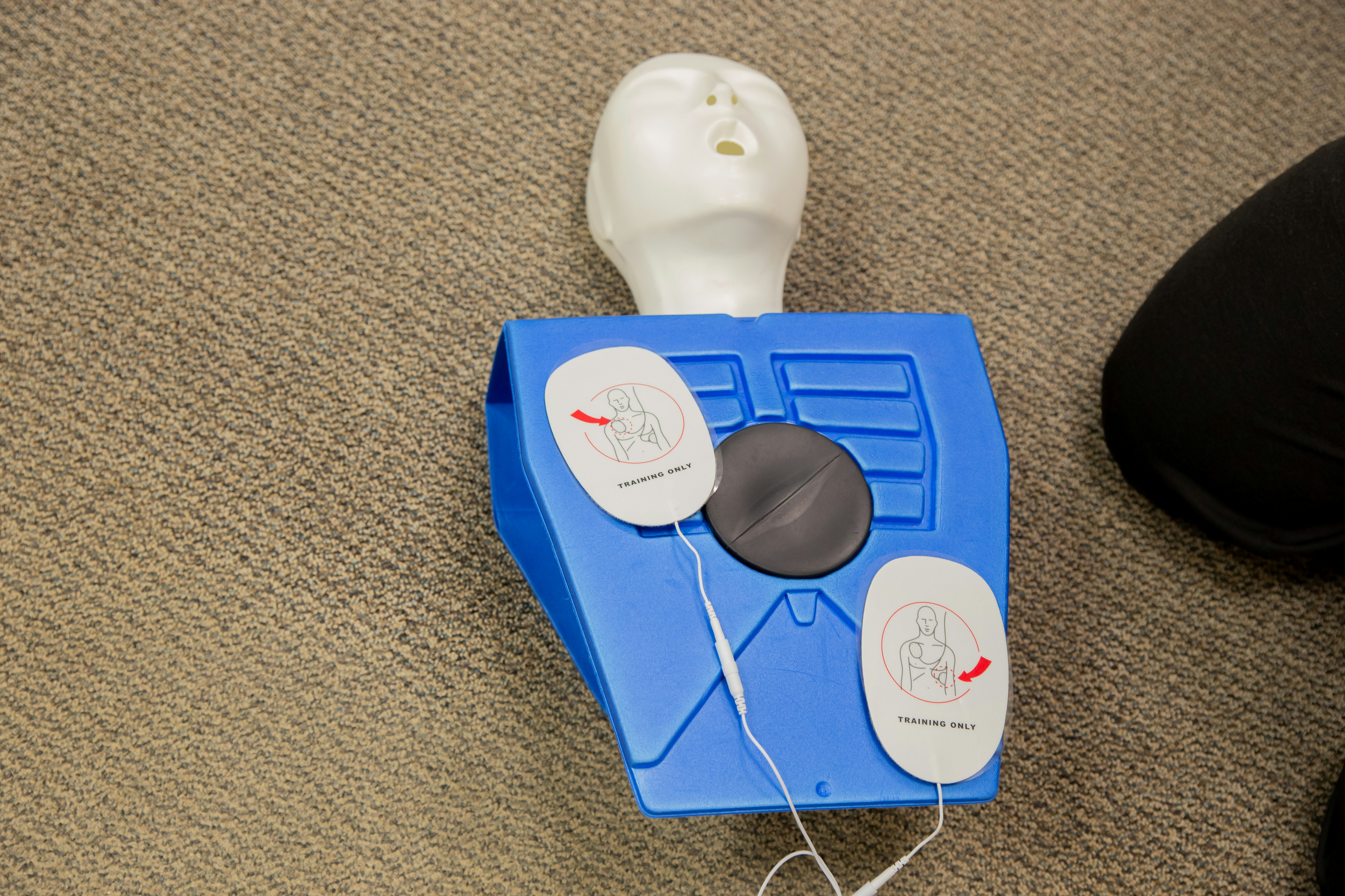 Dummy doll with AEC pats on the chest for CPR training.