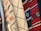 Multiple pieces of fabric with various woven patterns. The fabrics feature intricate designs, including geometric shapes, lines, and crosses. The colors range from neutral tones like beige and white to vibrant hues such as red, blue, and green.