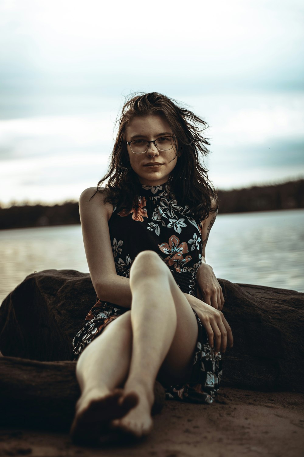 a woman sitting on a rock by the water