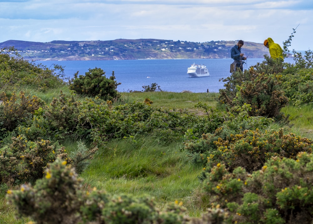 a person standing on a hill looking at a boat on the water