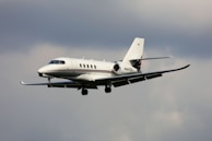 A sleek private jet gliding smoothly above fluffy white clouds.