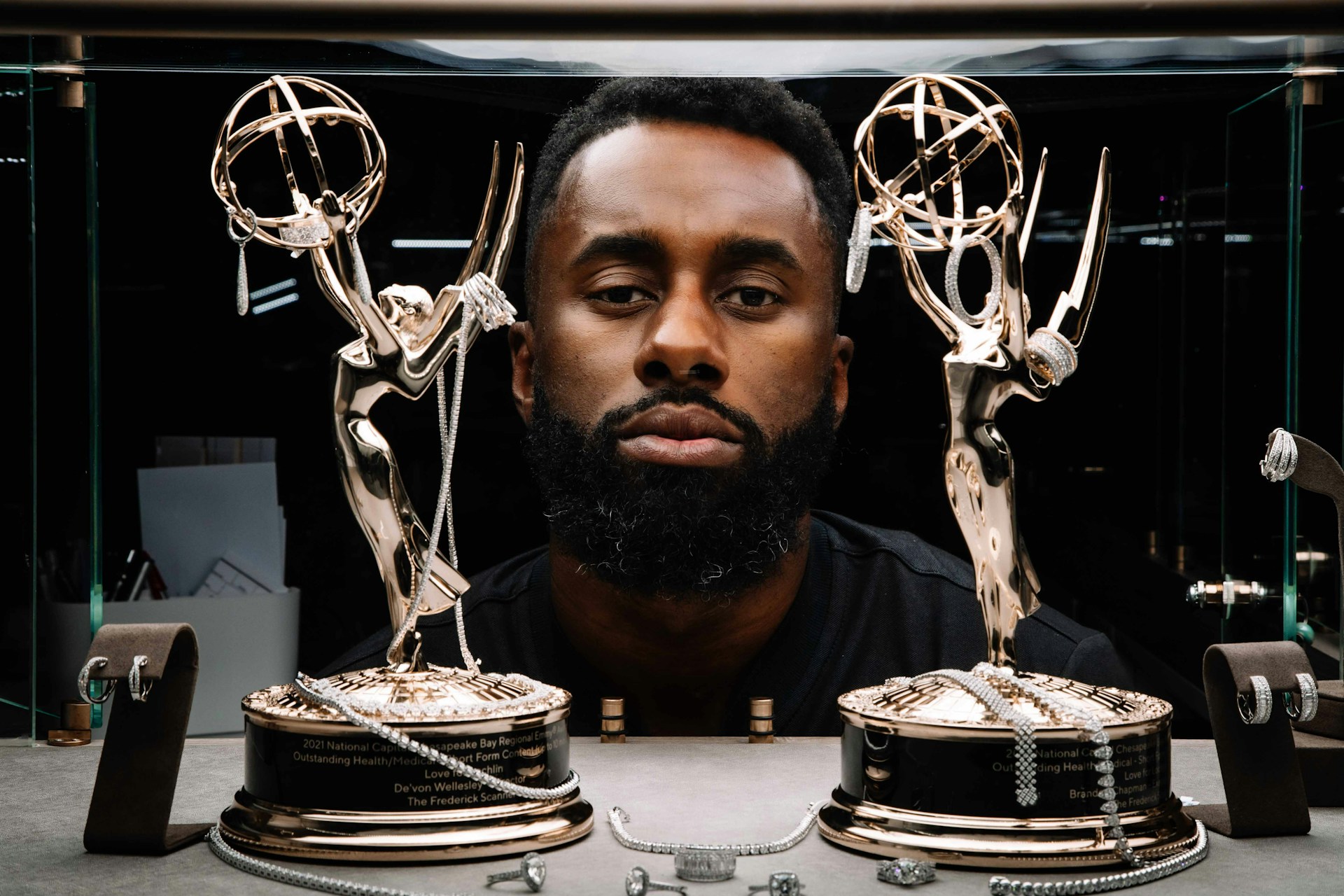 a person with a beard and a mustache behind a table with trophies