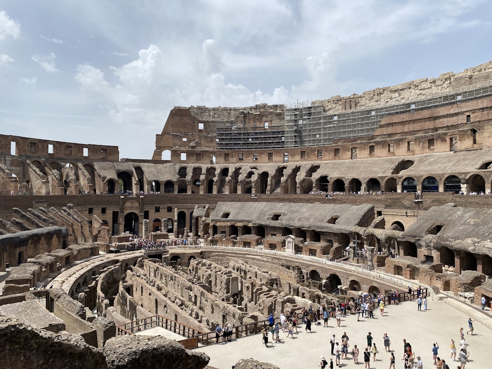 un gran edificio antiguo con muchas personas con el Coliseo al fondo