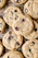 Close-up of a warm, freshly baked cookie with chocolate chips on a rustic wooden table.