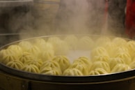 A steaming basket filled with freshly made chicken buns ready to serve.