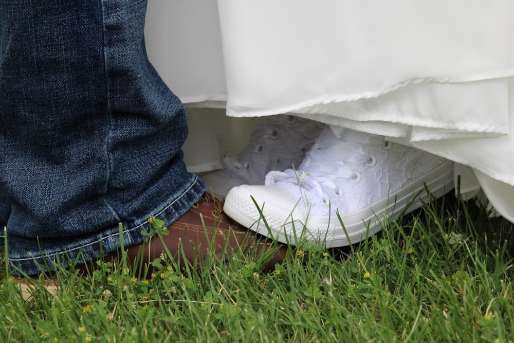 a person's legs and feet in a white shoe on grass