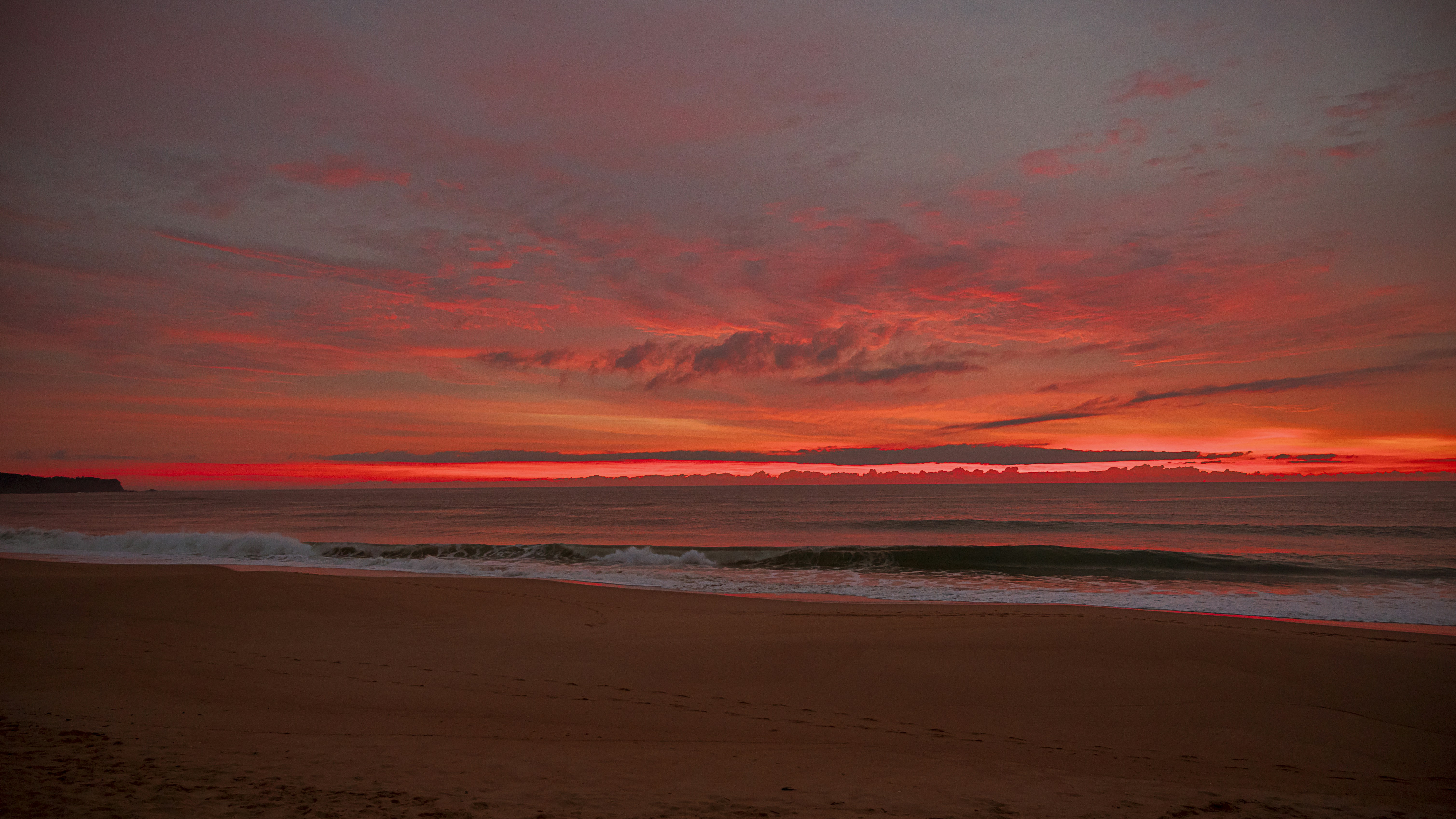 a beach with waves and a sunset