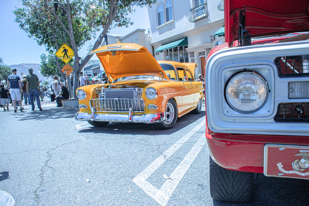 a yellow car parked next to a red truck