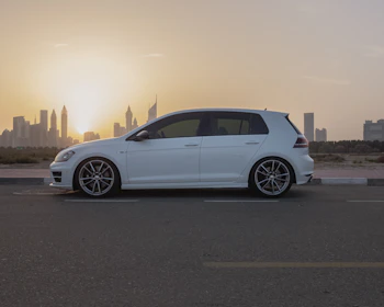 A compact economy car parked in front of a city skyline at sunset.