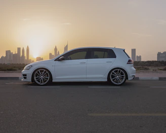 A clean, modern car parked in front of a city skyline at sunset.