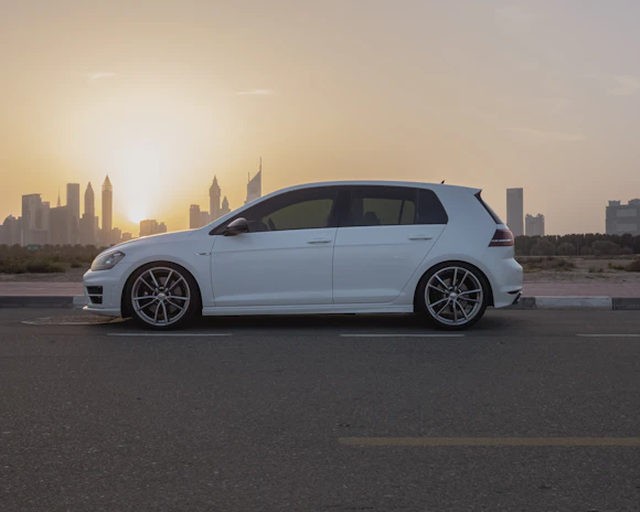 A clean, modern car parked in front of a city skyline at sunset.